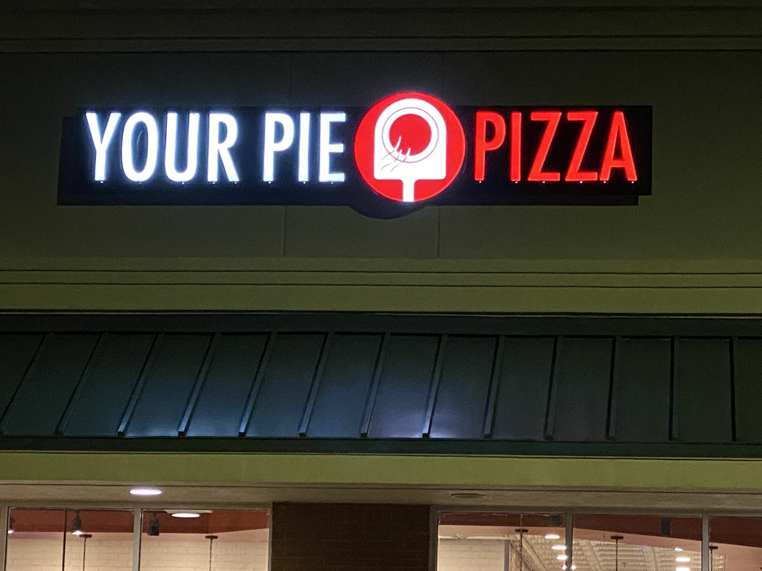 A sign for your pie pizza on the side of a building.